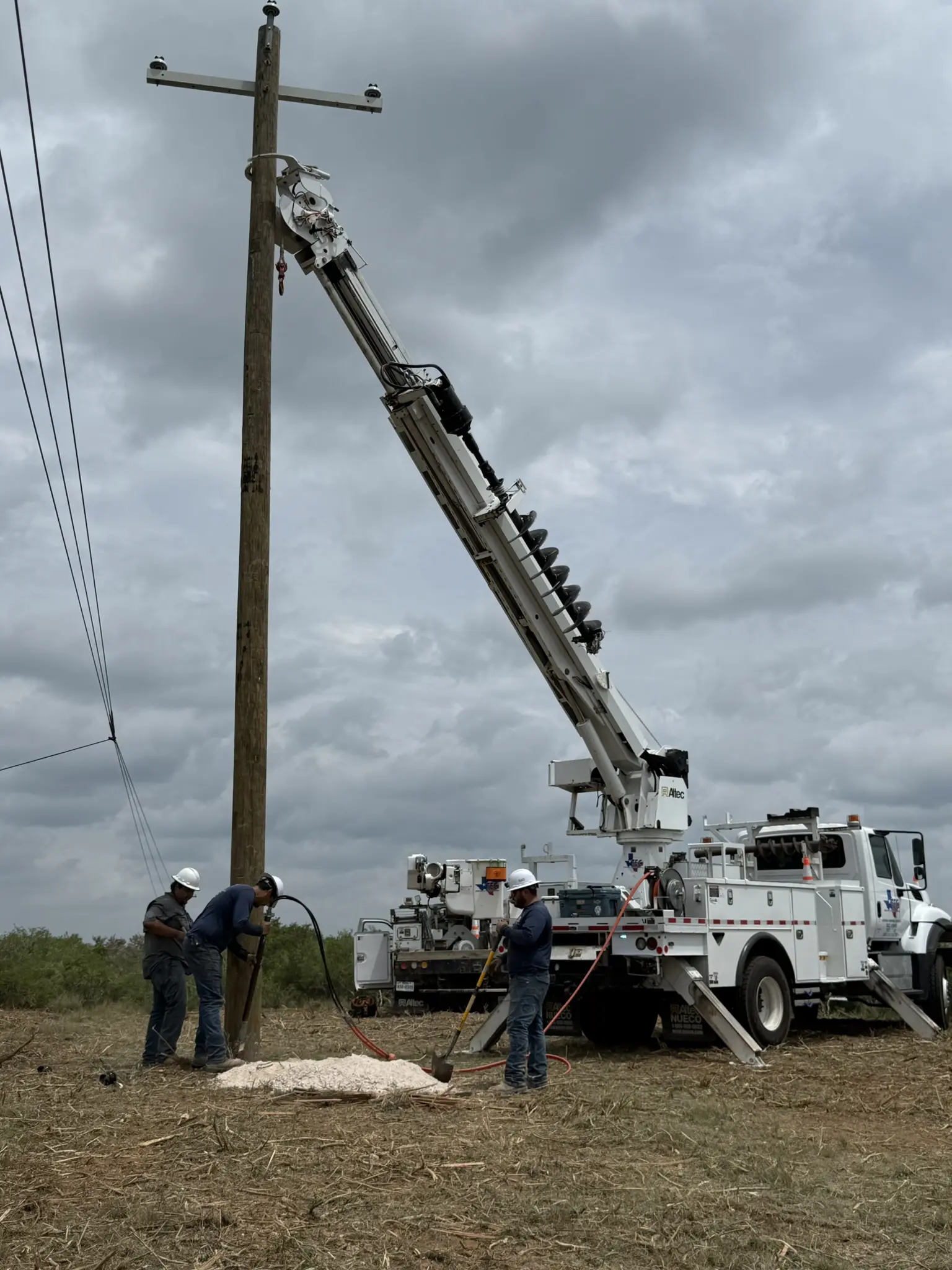 Utility workers installing a wooden power pole.